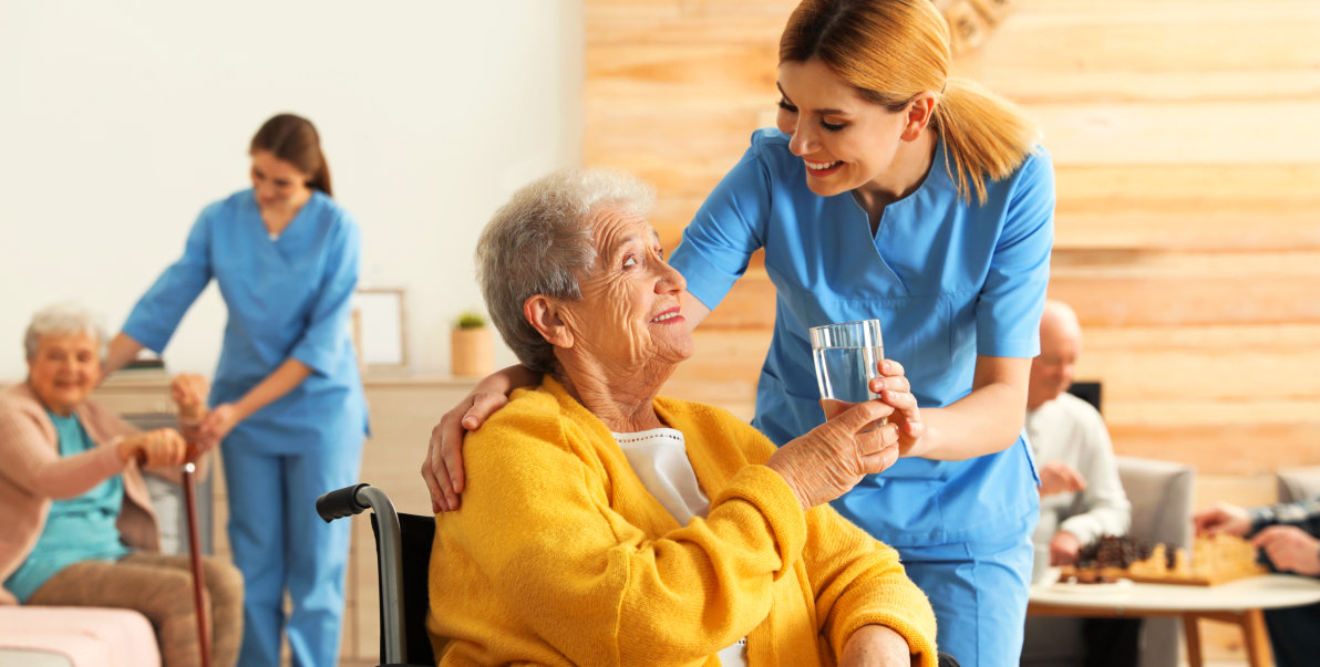 aide and elderly woman smiling at each other