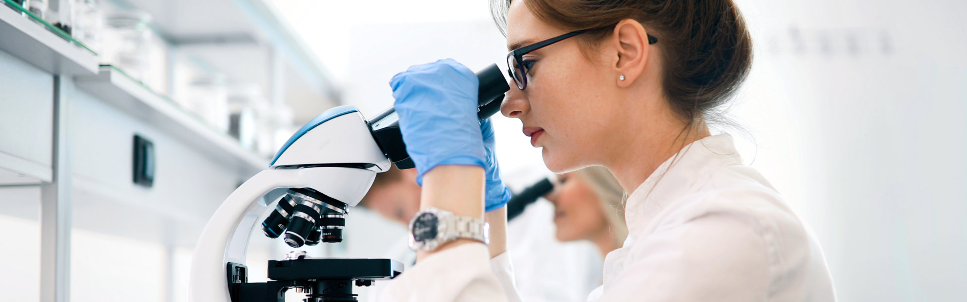 female scientist looking through microscope in laboratory